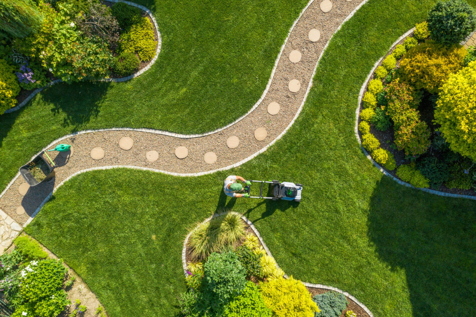 Big Garden Grass Field Mowing by Caucasian Gardener Man mowing lawn in landscaped garden.