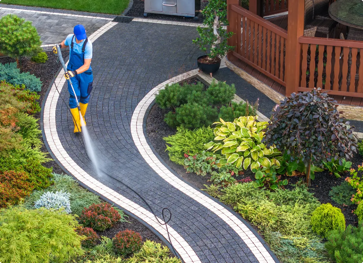 Rectangle 3 Gardener pressure washing a curved stone path.
